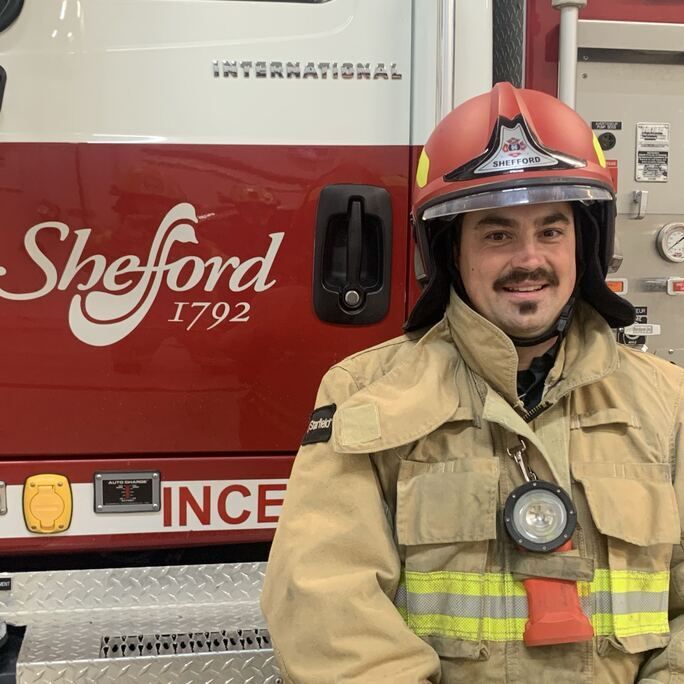 Photo of firefighter in full equipment smiling to camera.