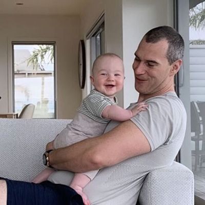 Father on couch holding smiling infant.