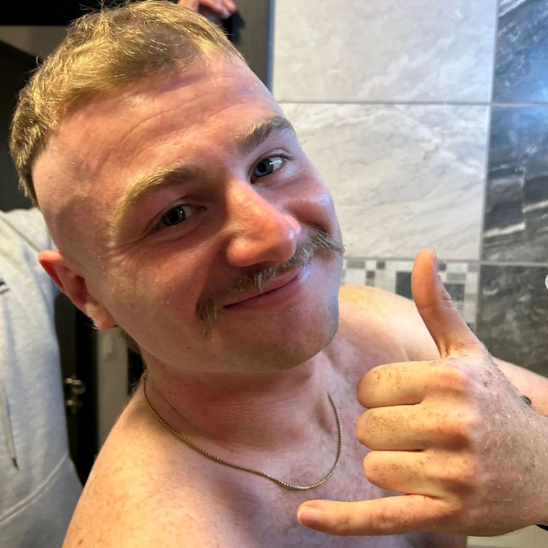 Photo of a man with a smart-looking moustache, smiling to camera.